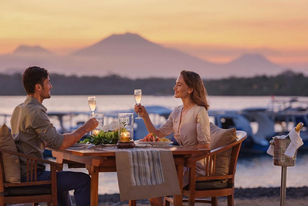 A couple having romantic dinner and champagne by the beach at Mimpi Resort Menjangan in West Bali